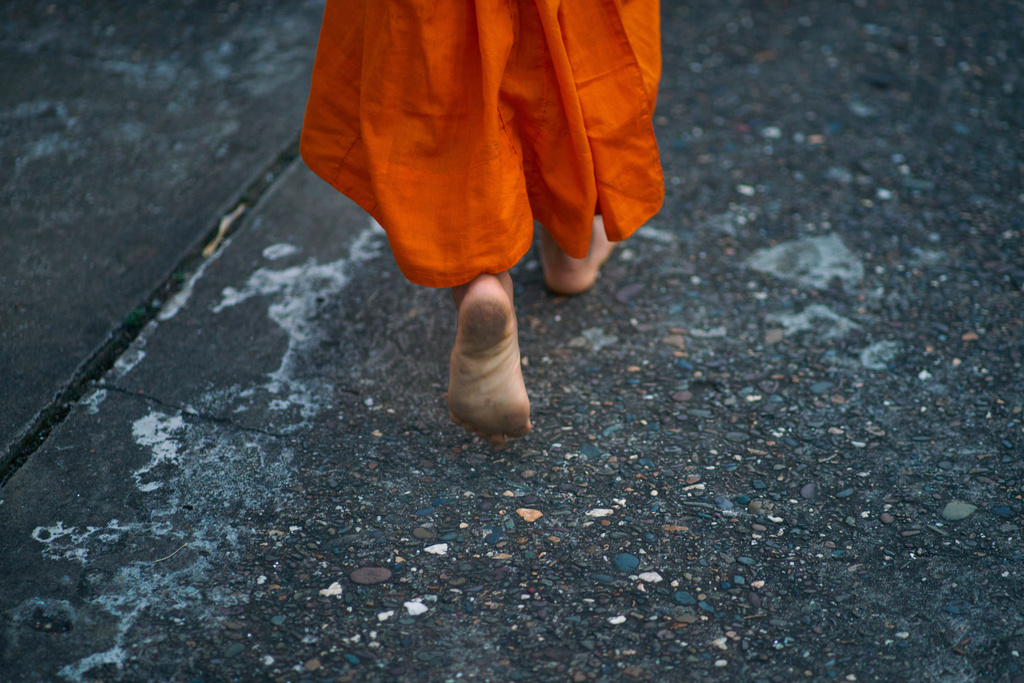 A novice Buddhist monk walks barefeet seeking alms early morning in Luang Prabang, Laos, Tuesday, Nov. 4, 2025. (AP Photo/Eugene Hoshiko)