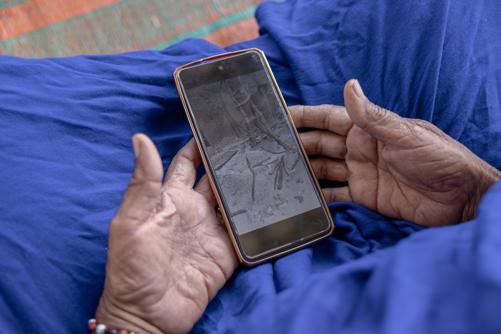Afay, a Malian refugee, shows images of her burned village after Africa Corps razed the marketplace to the ground, she said while sitting at a camp in Douankara, Mauritania, Friday, Nov. 7, 2025. (AP Photo/Caitlin Kelly)