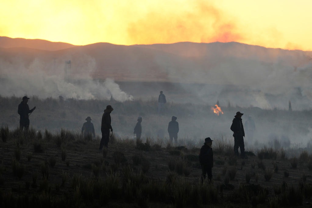FILE- Anti-government protesters standing in a field are silhouetted against clouds of tear gas launched by police, near El Alto, Bolivia, May 16, 2026. (AP Photo/Juan Karita, File)