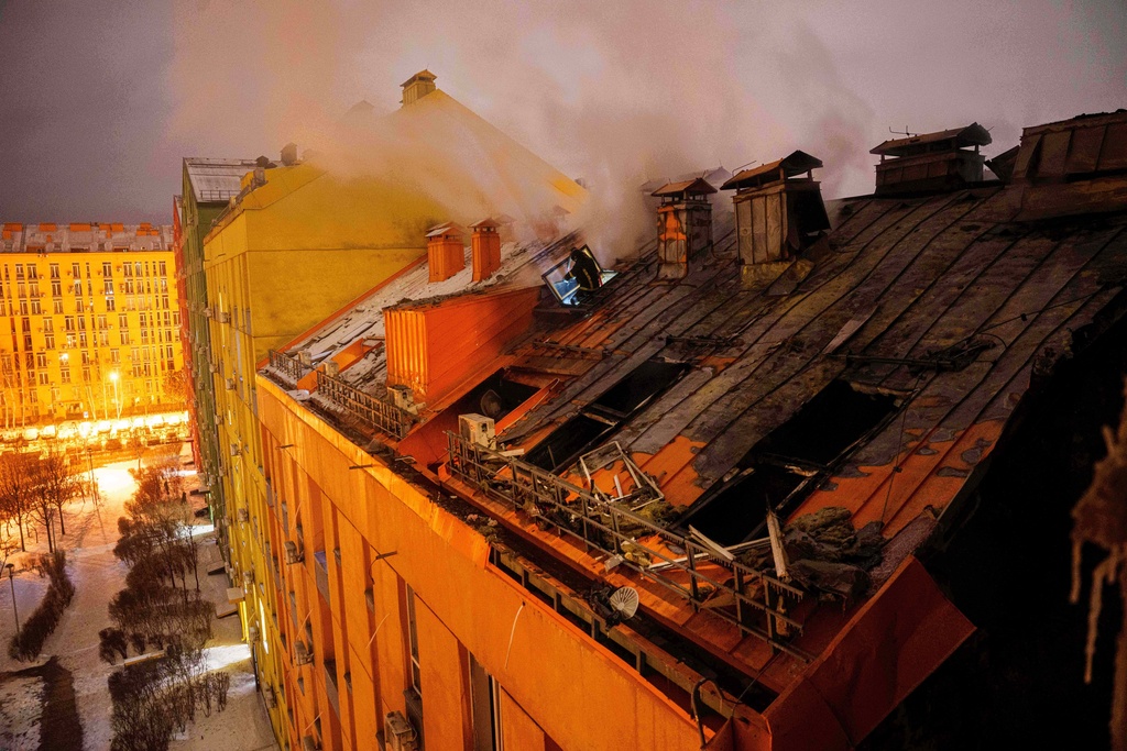 A rescue worker tries to put out a fire at a residential building damaged after a Russian strike on Kyiv, Ukraine, on Friday, Jan. 9, 2026. (AP Photo/Evgeniy Maloletka)