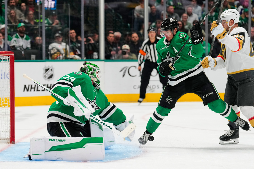 Dallas Stars goaltender Jake Oettinger (29) reaches to glove a shot as Miro Heiskanen (4) helps against pressure from Vegas Golden Knights left wing Ivan Barbashev (49) in the second period of an NHL hockey game in Dallas, Tuesday, March 10, 2026. (AP Photo/Tony Gutierrez)