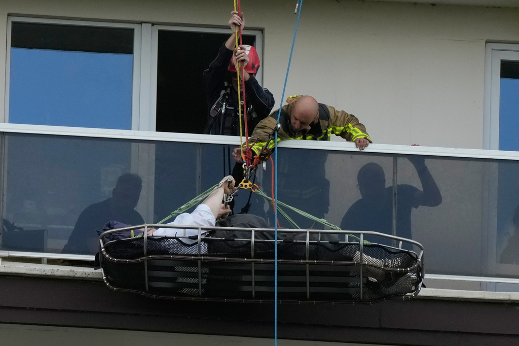 A person is evacuated from an upper floor after an apartment block fire in Linkeroever, Belgium, Wednesday, July 1, 2026. (AP Photo/Virginia Mayo)