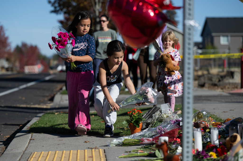 Children place flowers at a makeshift memorial outside Silver Rail Elementary in Bend, Ore., Friday, Oct. 16, 2026, a day after a deadly shooting. (AP Photo/Joe Kline)