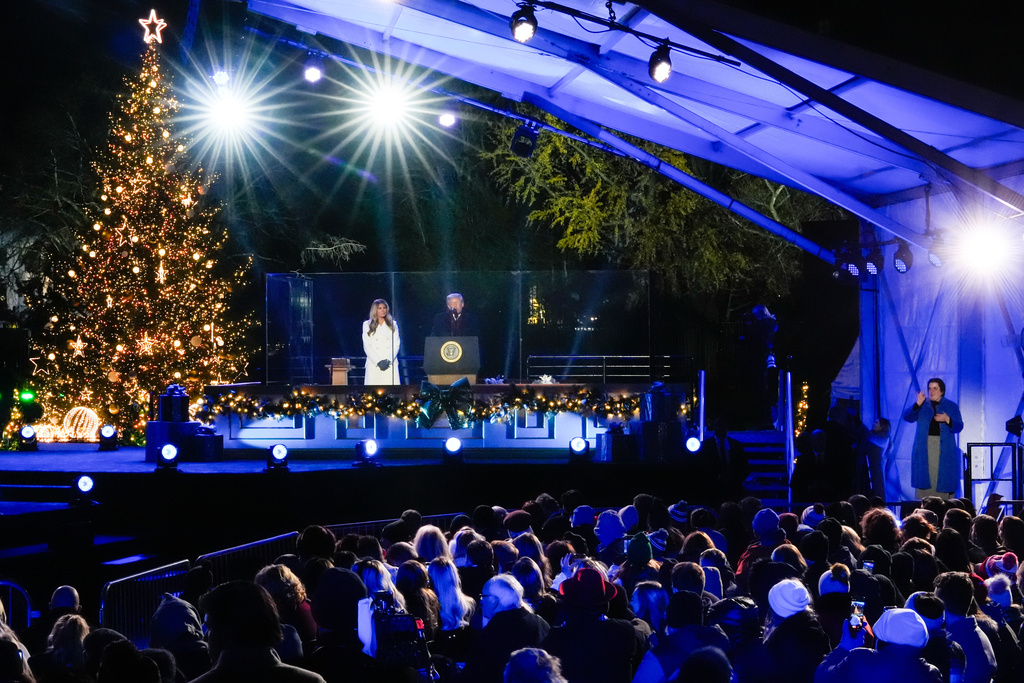 An American Sign Language interpreter, right, signs as President Donald Trump, accompanied by first lady Melania Trump, speaks following the lighting of the National Christmas Tree on the Ellipse, Thursday, Dec. 4, 2025, near the White House in Washington. (AP Photo/Julia Demaree Nikhinson)