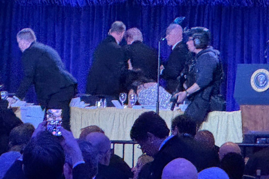 U.S. Secret Service agents surround President Donald Trump, third from left, as he is taken from the stage after a shooting incident outside the ballroom during the White House Correspondents Dinner, Saturday, April 25, 2026, in Washington. (AP Photo/Mark Schiefelbein)