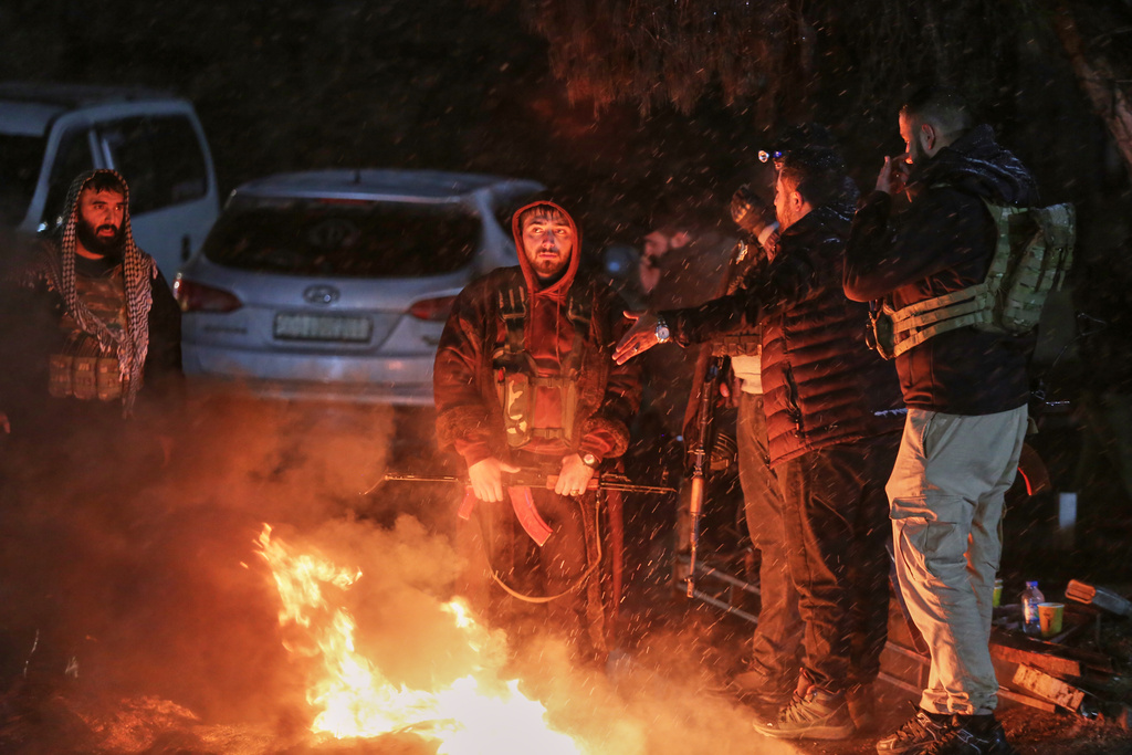 Armed Kurdish volunteers stand guard at a checkpoint while patrolling overnight in Qamishli, northeastern Syria, late Thursday, Jan. 22, 2026. (AP Photo/Baderkhan Ahmad)