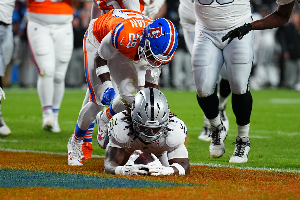 Las Vegas Raiders running back Ashton Jeanty scores as Denver Broncos cornerback Ja'Quan McMillian (29) defends during the first half of an NFL football game Thursday, Nov. 6, 2025, in Denver. (AP Photo/Jack Dempsey)
