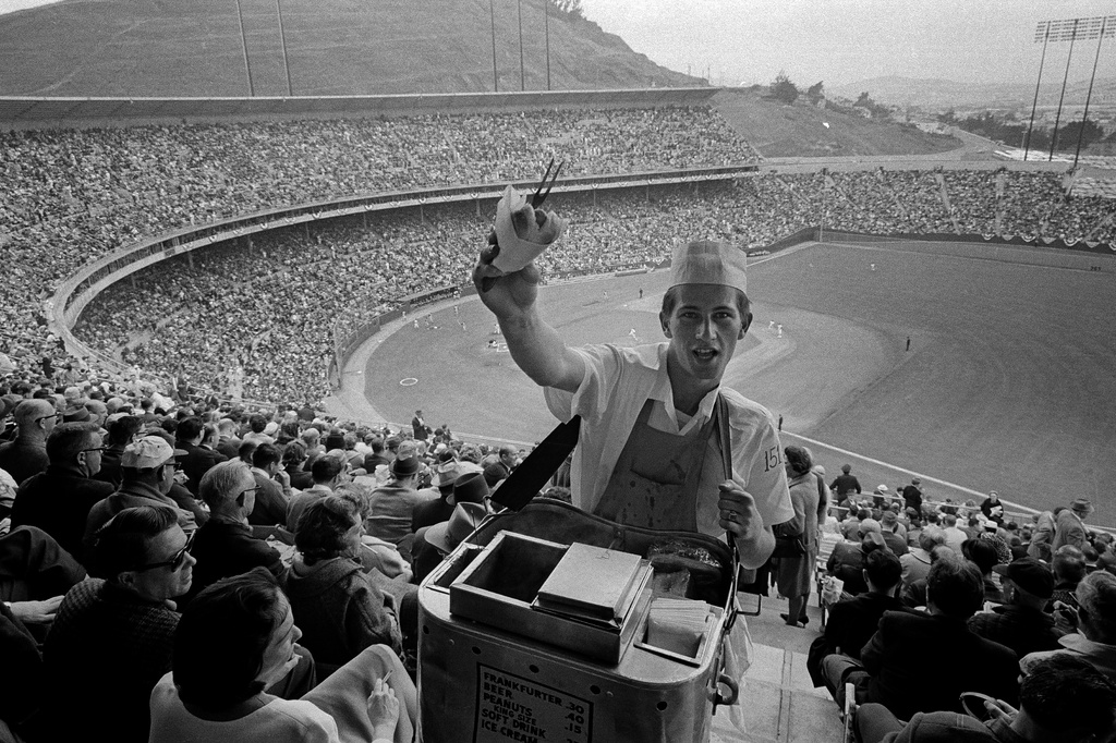 FILE - A hot dog vendor plies his wares amid a large crowd that turned out at Candlestick Park in San Francisco to watch the San Francisco Giants play their opening home game of the 1965 season against the Pittsburgh Pirates, April 20, 1965. (AP Photo, File)