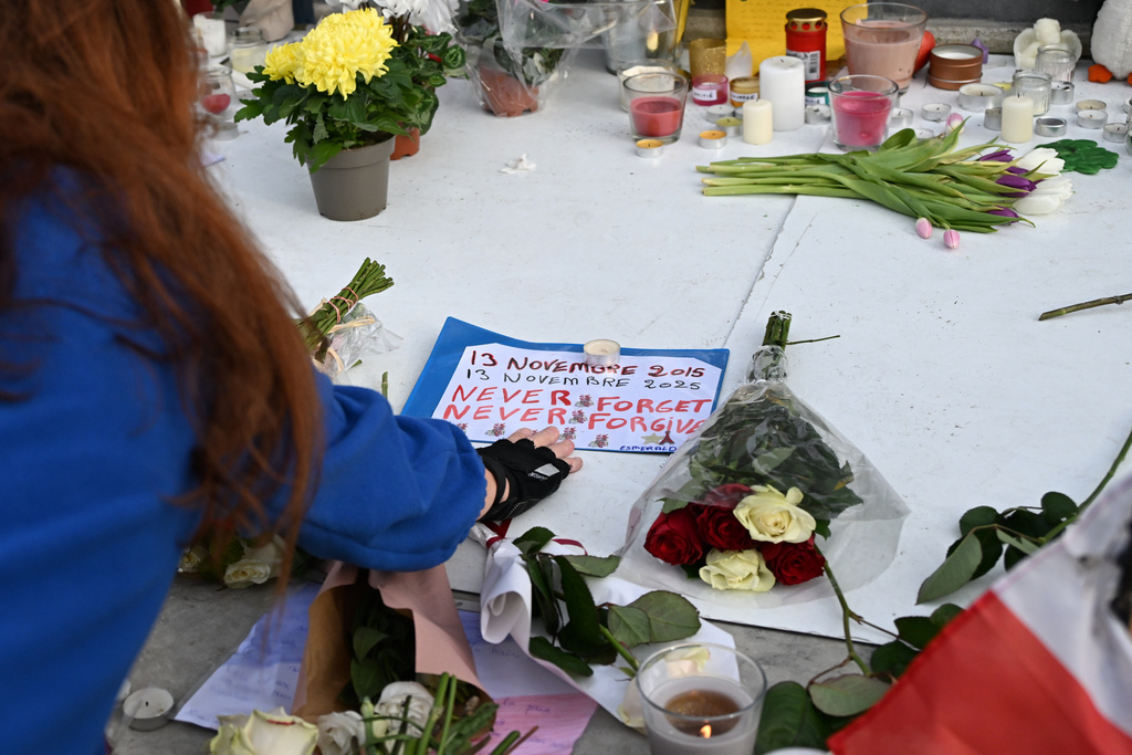 A woman touches a message at the statue of the Place de la Republique (Republic Square) as Paris is marking the 10th anniversary of terrorist attacks that killed 132 people and injured hundreds, Thursday, Nov. 13, 2025 in Paris. (AP Photo/Emma Da Silva)