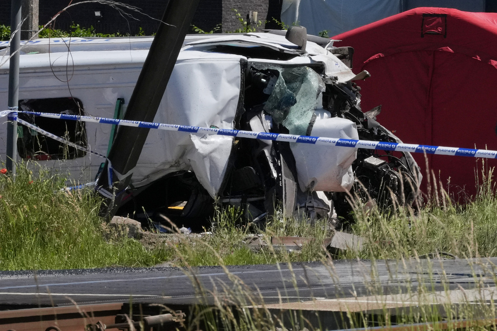 Police tape cordons off a level crossing where a train collided with a van in Buggenhout, Belgium, Tuesday, May 26, 2026. (AP Photo/Marius Burgelman)