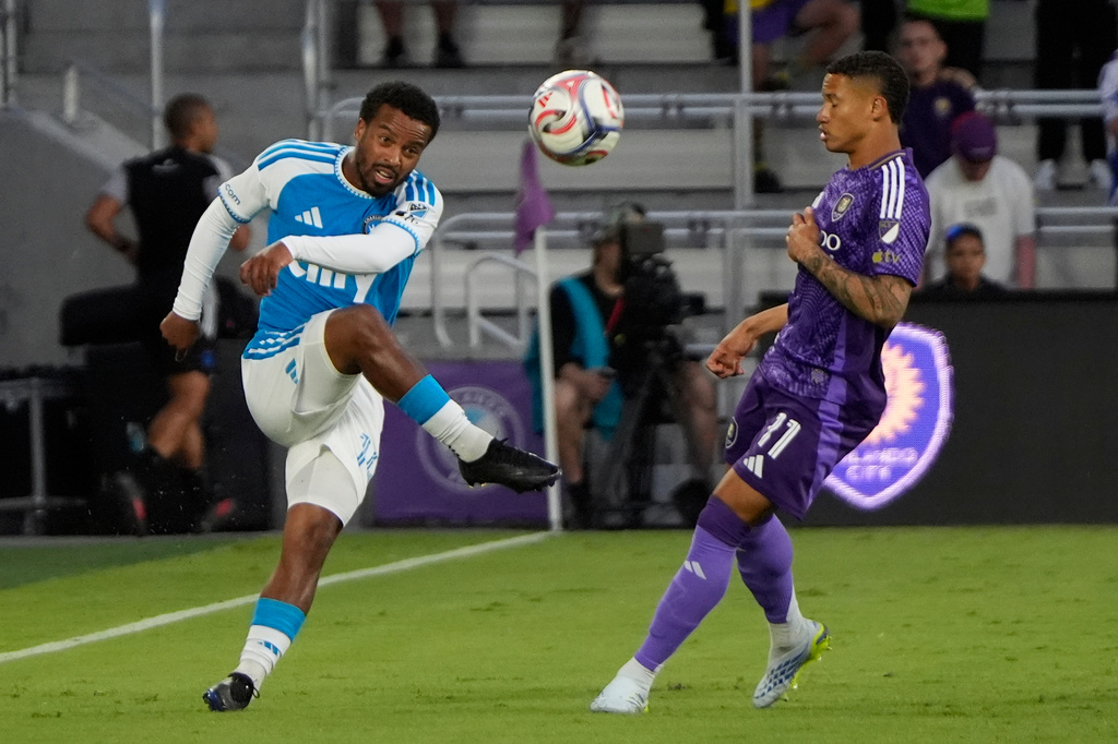 Charlotte FC defender Nathan Byrne, left, passes the ball over Orlando City SC midfielder Tiago during the first half of an MLS soccer match, Wednesday, April 22, 2026, in Orlando, Fla. (AP Photo/John Raoux)
