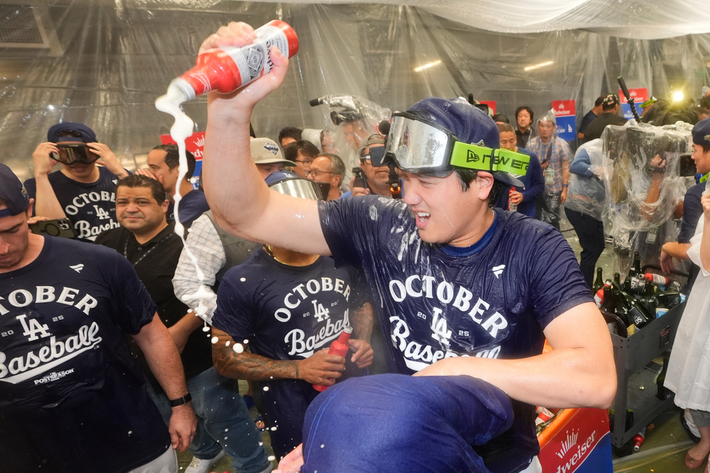 Los Angeles Dodgers' Shohei Ohtani, right, celebrates in the clubhouse after a win over the Cincinnati Reds in Game 2 of the National League Wild Card baseball playoff series Wednesday, Oct. 1, 2025, in Los Angeles. (AP Photo/Mark J. Terrill)