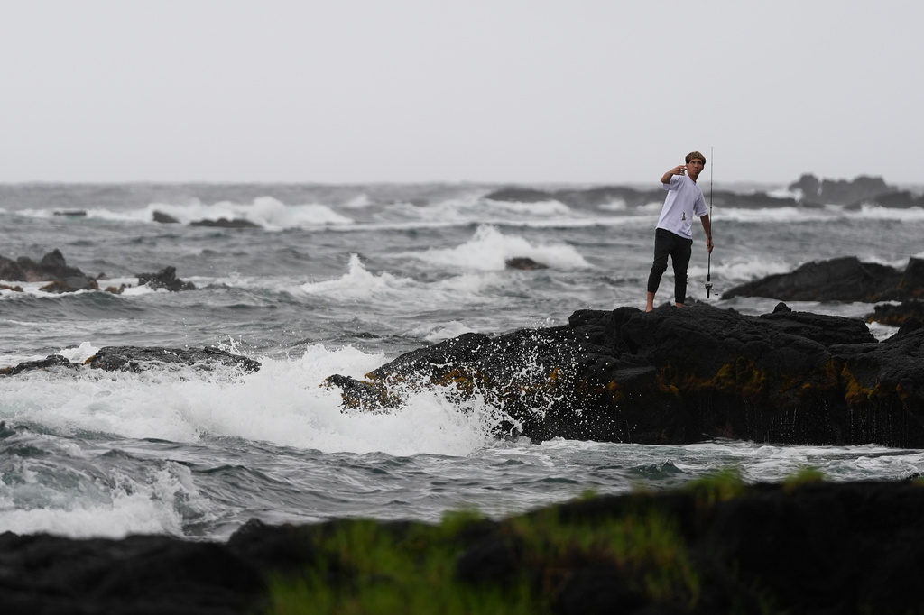 Chase Gabin fishes among the rocks as Hurricane Nolo sits nearby Friday, Sept. 25, 2026, in Hilo, Hawaii. (AP Photo/Gregory Bull)
