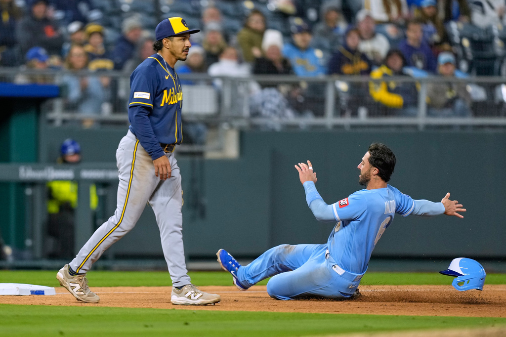 Kansas City Royals' Jonathan India, right, beats the tag by Milwaukee Brewers third baseman David Hamilton to advance to third on a single by Carter Jensen during the sixth inning in the second baseball game of a doubleheader Saturday, April 4, 2026, in Kansas City, Mo. (AP Photo/Charlie Riedel)
