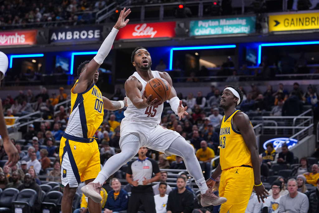 Cleveland Cavaliers guard Donovan Mitchell (45) shoots between Indiana Pacers guard Bennedict Mathurin (00) and forward Pascal Siakam (43) during the first half of an NBA basketball game in Indianapolis, Monday, Dec. 1, 2025. (AP Photo/Michael Conroy)