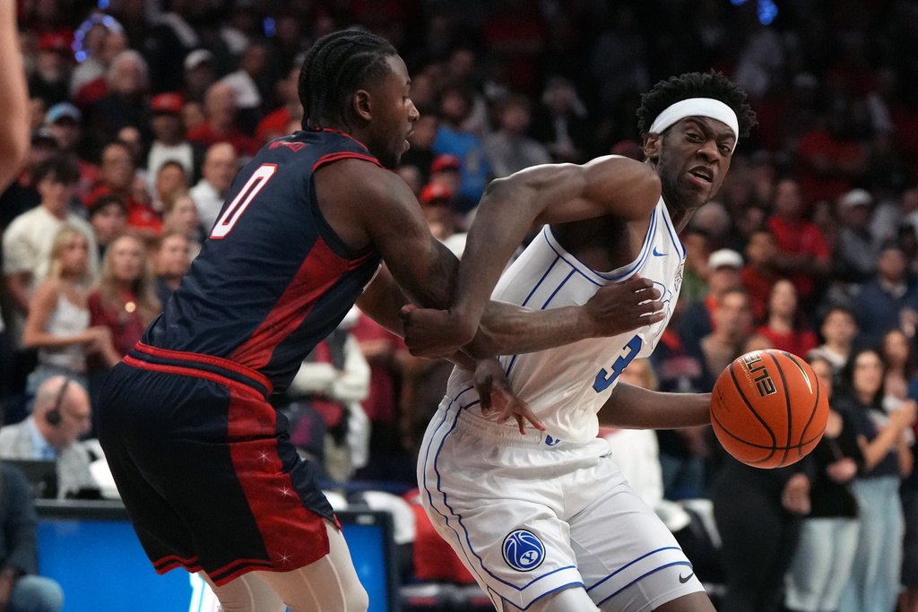 BYU forward AJ Dybantsa (3) drives on Arizona guard Jaden Bradley during the first half of an NCAA college basketball game, Wednesday, Feb. 18, 2026, in Tucson, Ariz. (AP Photo/Rick Scuteri)