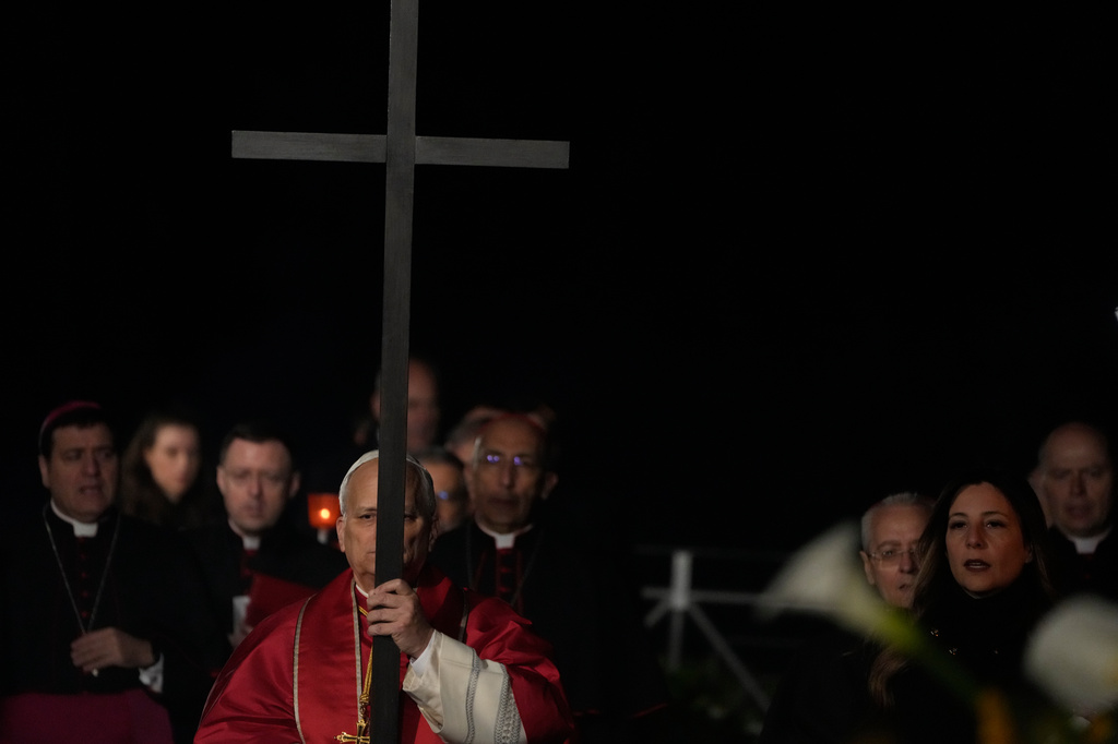 Pope Leo XIV carries a lightweight, 1.5-meter (5-foot) wooden cross during the Via Crucis, the torchlit Good Friday Stations of the Cross procession at the Colosseum in Rome, Friday, April 3, 2026, which symbolically retraces Jesus Christ's steps to his crucifixion on Calvary in Jerusalem. (AP Photo/Gregorio Borgia)