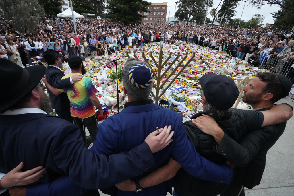 Mourners gather at a menorah lighting ceremony at a floral memorial for victims of Sunday's shooting, at the Bondi Pavilion at Bondi Beach on Tuesday, Dec. 16, 2025, in Sydney, Australia. (AP Photo/Mark Baker)