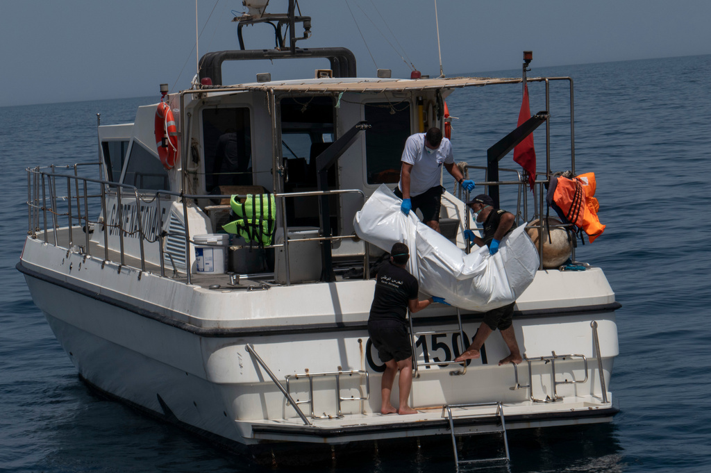 Tunisian national guard members recover a drowned body during a search operation after a boat carrying migrants capsized off the country's southeastern coast, near Zarzis, Tunisia, Sunday, Aug. 23, 2026. (AP Photo/Bassem Aouini)