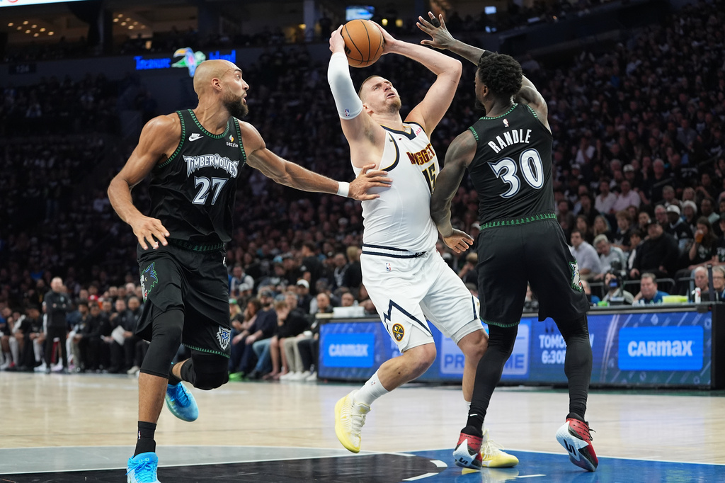 Denver Nuggets center Nikola Jokic (15) works toward the basket as Minnesota Timberwolves center Rudy Gobert (27) and forward Julius Randle (30) defend during the first half in Game 3 of a first-round NBA basketball playoff series, Thursday, April 23, 2026, in Minneapolis. (AP Photo/Abbie Parr)