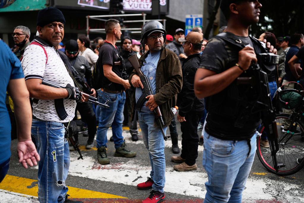 Pro-government armed civilians attend a protest demanding the release of President Nicolas Maduro and first lady Cilia Flores, the day after U.S. forces captured and flew them to the United States, in Caracas, Venezuela, Sunday, Jan. 4, 2026. (AP Photo/Ariana Cubillos)
