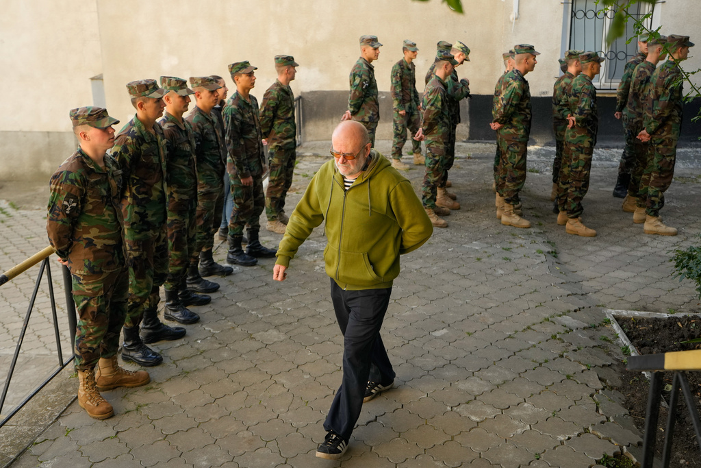 A man walks past a line of soldiers waiting to cast their vote outside a polling station during a parliamentary election, in Chisinau, Moldova, Sunday, Sept. 28, 2025. (AP Photo/Vadim Ghirda)