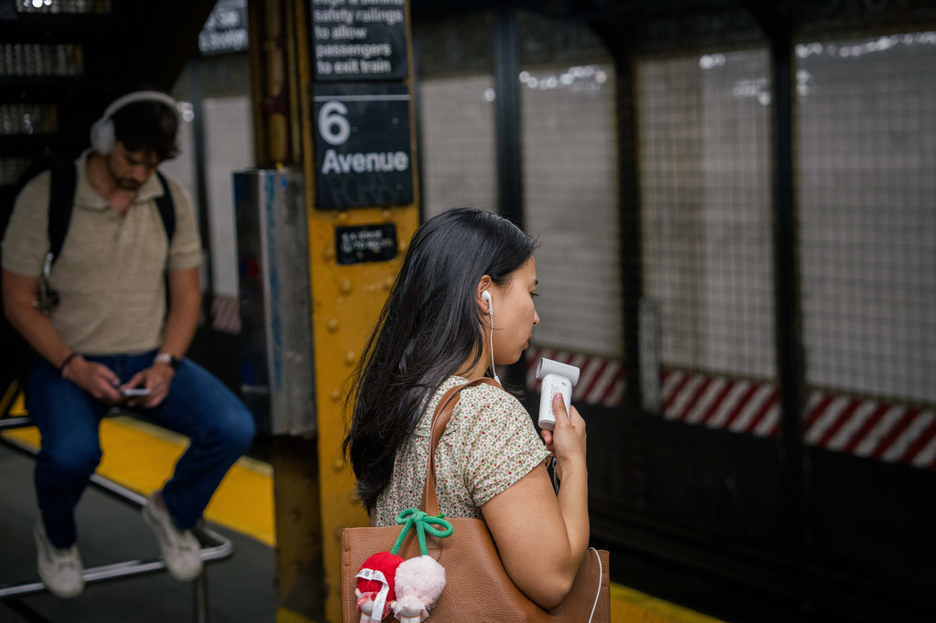 FILE - A person uses a mini electric fan as they wait on a subway platform during a heat advisory in New York, May 19, 2026. (AP Photo/Adam Gray, File)