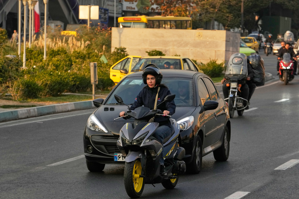 A woman drives her motorbike in downtown Tehran, Iran, Saturday, Nov. 8, 2025. (AP Photo/Vahid Salemi)