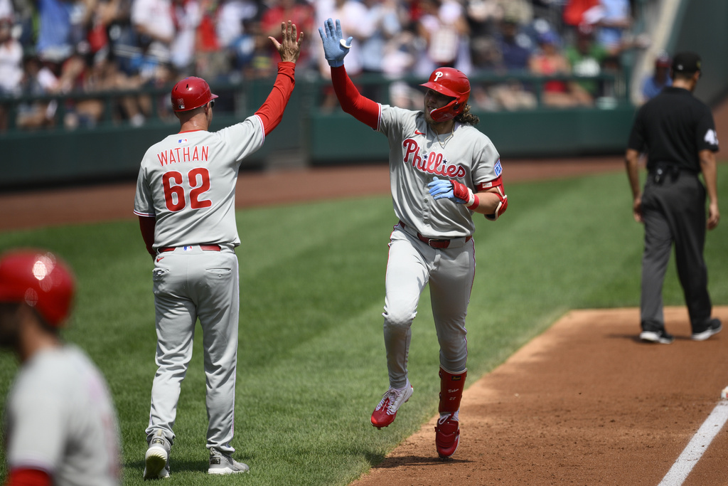Philadelphia Phillies' Alec Bohm, right, celebrates his three-run home run with third base coach Dusty Wathan (62) as he rounds the bases during the second inning of a baseball game against the Washington Nationals, Sunday, Aug. 17, 2025, in Washington. (AP Photo/Nick Wass)