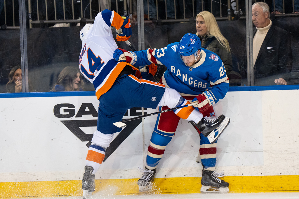 New York Islanders center Bo Horvat (14) and New York Rangers defenseman Adam Fox (crash into each other during a fight for the puck in the first period of an NHL hockey game, Saturday, Nov. 8, 2025, in New York. (AP Photo/Angelina Katsanis)