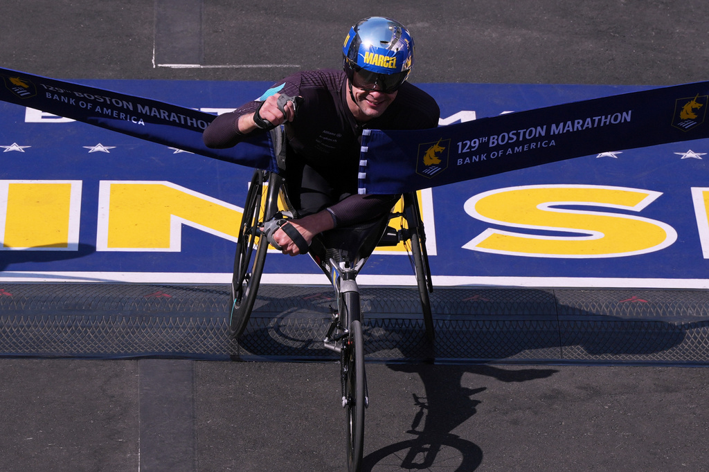 FILE - Marcel Hug, of Switzerland, breaks the tape to win the men's wheelchair division during the Boston Marathon, Monday, April 21, 2025, in Boston. (AP Photo/Charles Krupa, File)