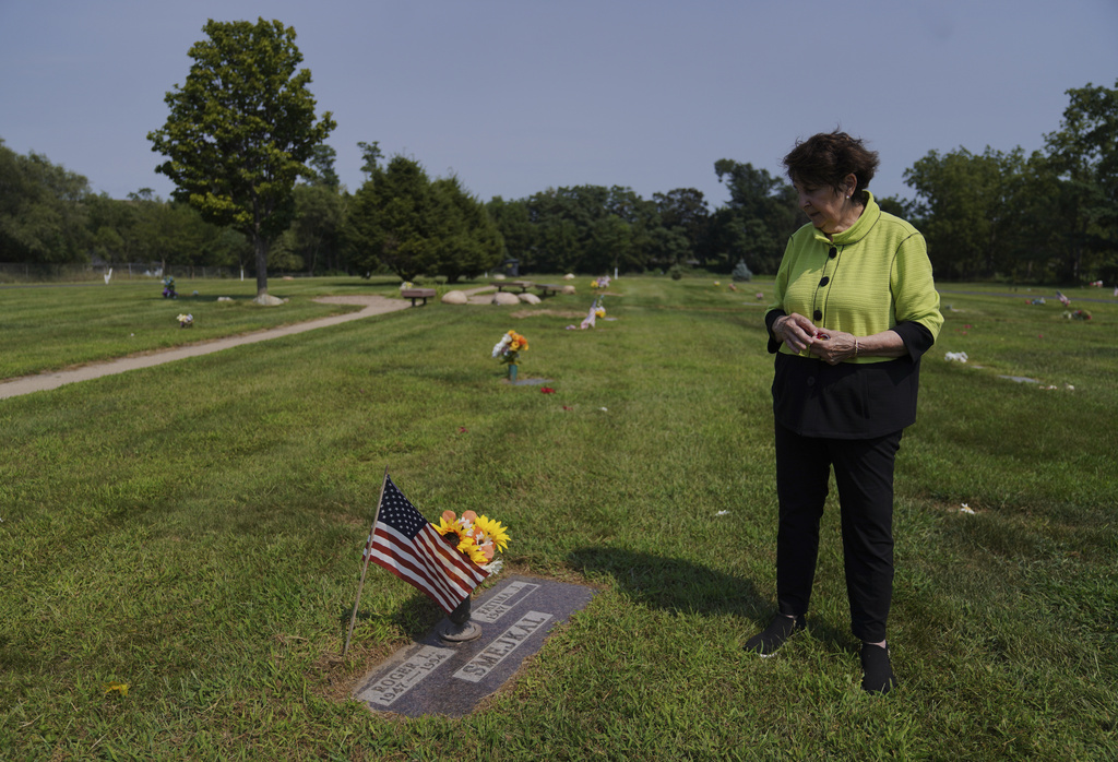Fatima Igram Smejkal, whose family immigrated from present-day Lebanon to the United States in the early 1900s, stands beside her husband's grave in the Muslim National Cemetery, established in the 1940s, in Cedar Rapids, Iowa, on Friday, Aug. 8, 2025. (AP Photo/Jessie Wardarski)