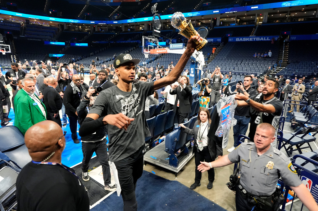 San Antonio Spurs forward Victor Wembanyama walks over to Spurs fans as he holds his MVP trophy as he celebrates after Game 7 of the Western Conference finals of the NBA basketball playoffs series win against the Oklahoma City Thunder, Saturday, May 30, 2026, in Oklahoma City. (AP Photo/Tony Gutierrez)