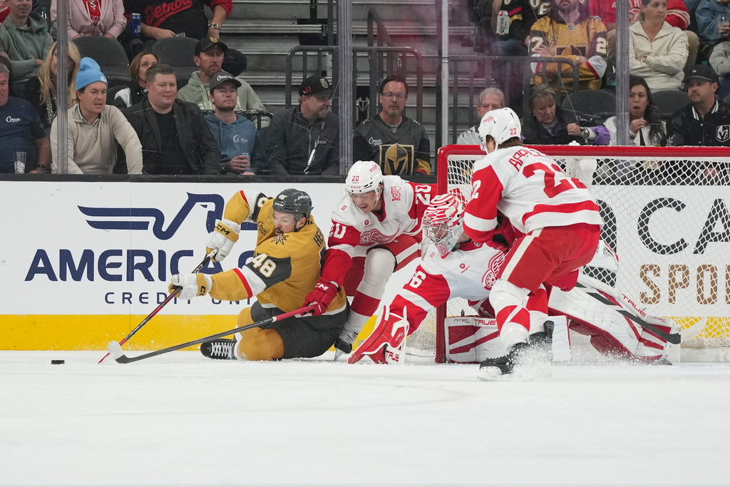 Vegas Golden Knights center Tomas Hertl (48) battles for the puck with Detroit Red Wings defenseman Albert Johansson (20) and goaltender John Gibson (36) in the first period of an NHL hockey game Tuesday, Nov. 4, 2025, in Las Vegas. (AP Photo/Candice Ward)
