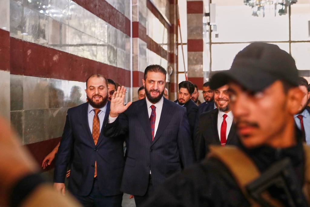 Syrian interim President Ahmad al-Sharaa waves as he enters a polling station where electoral college members are voting in a parliamentary election in Damascus, Syria, Sunday, Oct. 5, 2025. (AP Photo/Omar Sanadiki)