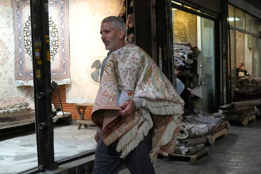 A man carries a carpet in hand-woven carpets market at Tehran's traditional main bazaar, Iran, Saturday, Aug. 8, 2026. (AP Photo/Vahid Salemi)