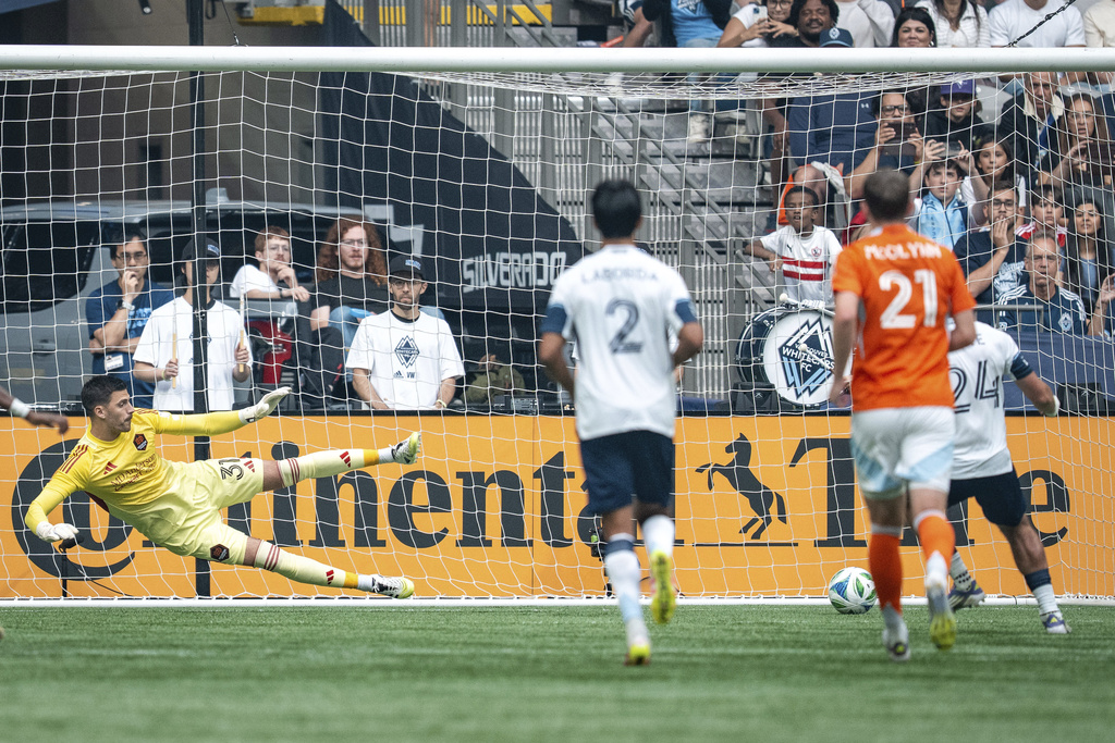 Vancouver Whitecaps' Brian White, right, scores on Houston Dynamo goalkeeper Jonathan Bond (31) during the first half of an MLS soccer match in Vancouver, British Columbia, Sunday, Aug. 17, 2025. (Ethan Cairns/The Canadian Press via AP)