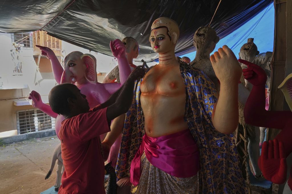 An artist attaches a colorful dress to an idol of a Hindu god ahead of the Durga Puja festival in New Delhi, India, Saturday, Sept. 20, 2025 (AP Photo/Manish Swarup)