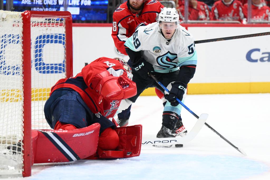 Seattle Kraken center Ben Meyers (59) battles for the puck against Washington Capitals goaltender Logan Thompson, left, during the second period of an NHL hockey game, Tuesday, Oct. 21, 2025, in Washington. (AP Photo/Nick Wass)