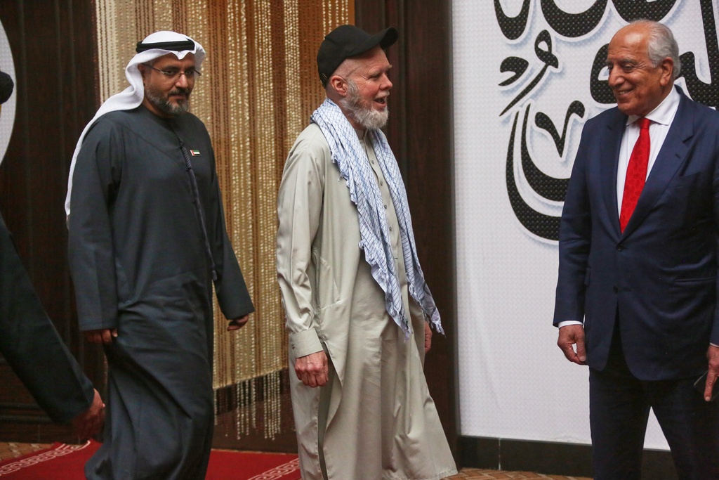 Accompanied by U.S. Special Representative for Afghanistan Zalmay Khalilzad, right, and UAE Ambassador in Kabul Saif Al Ketbi,, left, American Dennis Coyle, center, smiles after being released by Afghanistan's Taliban authorities, who had held him for over a year, before boarding a plane at the airport in Kabul, Afghanistan, Tuesday, March 24, 2026. (AP Photo/Mudassir Safi)