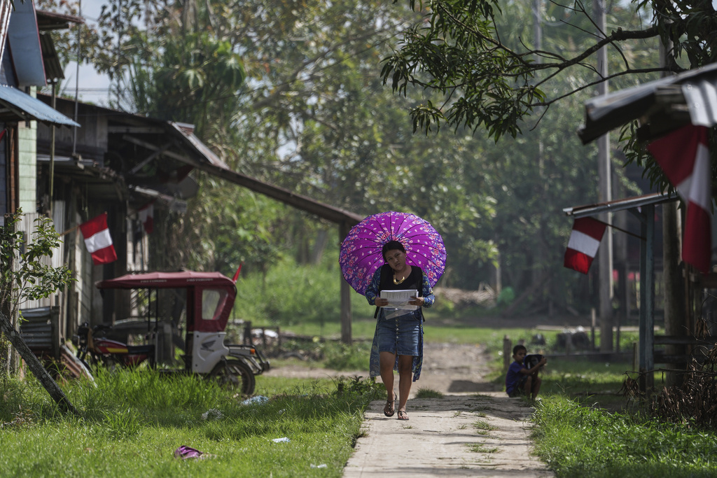 A woman shades herself with an umbrella in Santa Rosa, Peru, an island on the Amazon River at the triple border with Colombia and Brazil, Monday, Aug. 18, 2025. (AP Photo/Ivan Valencia)