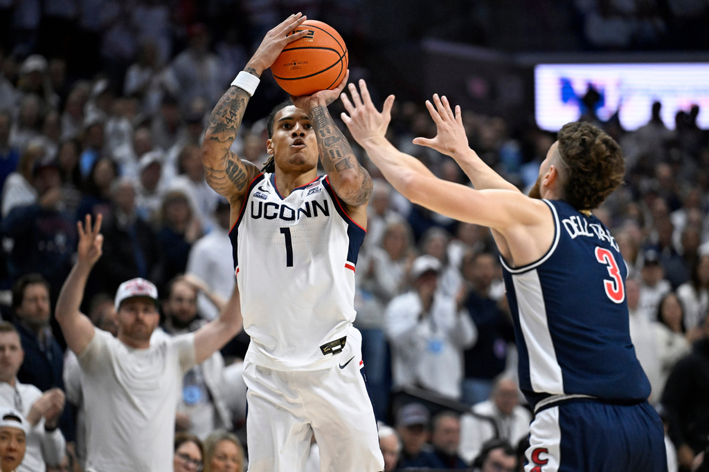 UConn guard Solo Ball (1) shoots over Arizona guard Anthony Dell'Orso (3) in the first half of an NCAA college basketball game, Wednesday, Nov. 19, 2025, in Storrs, Conn. (AP Photo/Jessica Hill)