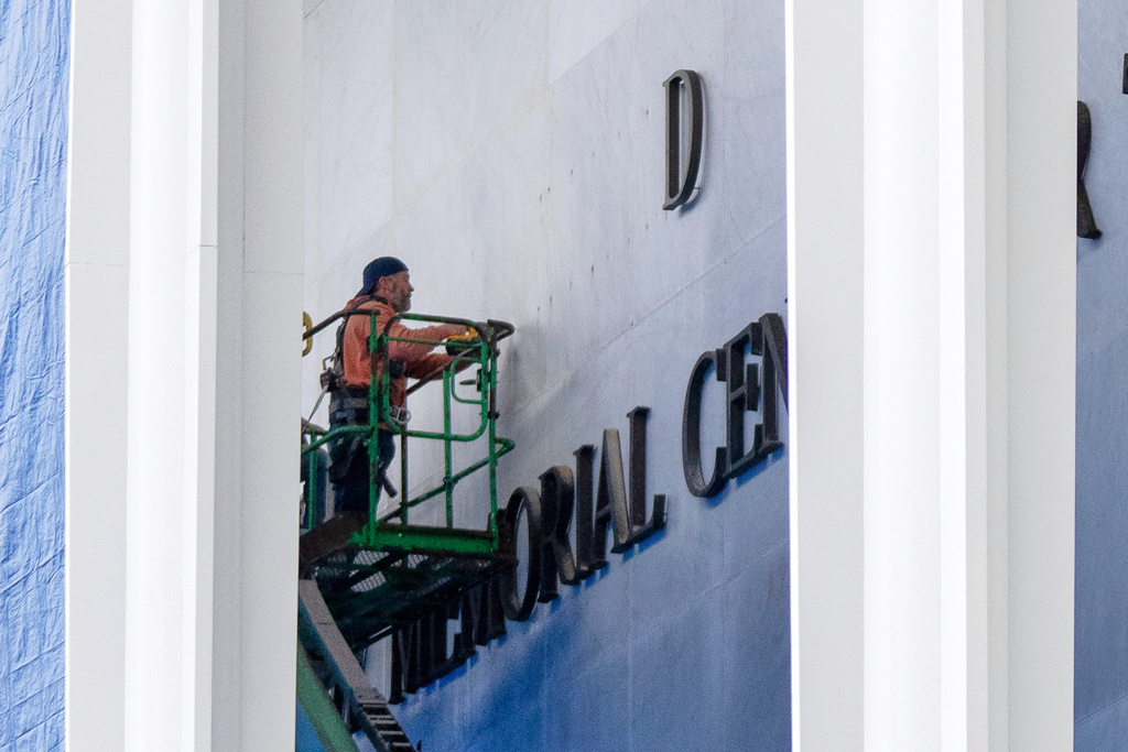 A worker drills holes near letters being installed above the signage on the Kennedy Center on Friday, Dec. 19, 2025, in Washington. (AP Photo/Mark Schiefelbein)