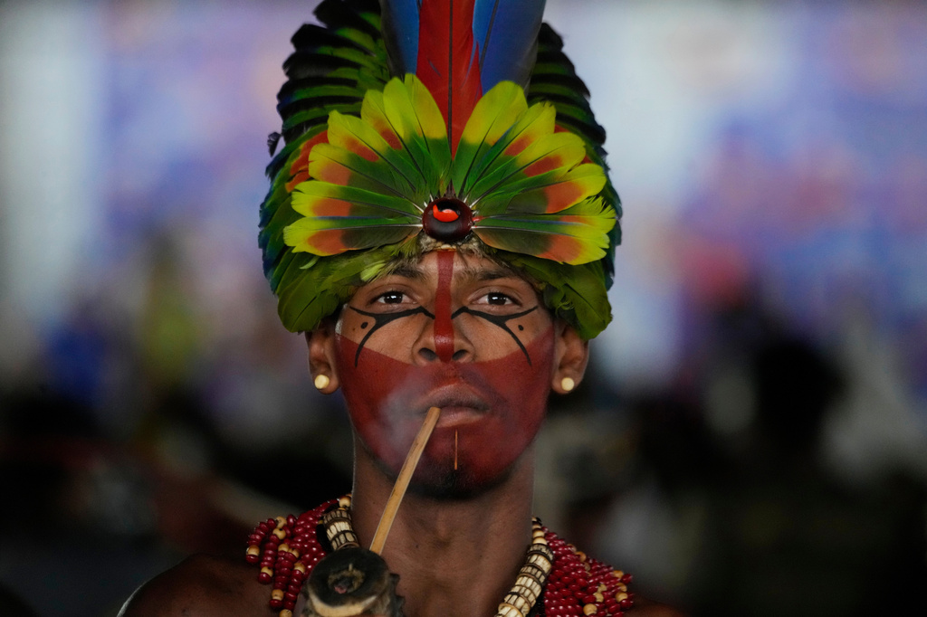 A Pataxo man smokes a traditional pipe before a march at the Acampamento Terra Livre 2026, an Indigenous mobilization focused on land rights and environmental protection, in Brasilia, Brazil, Thursday, April 9, 2026. (AP Photo/Eraldo Peres)
