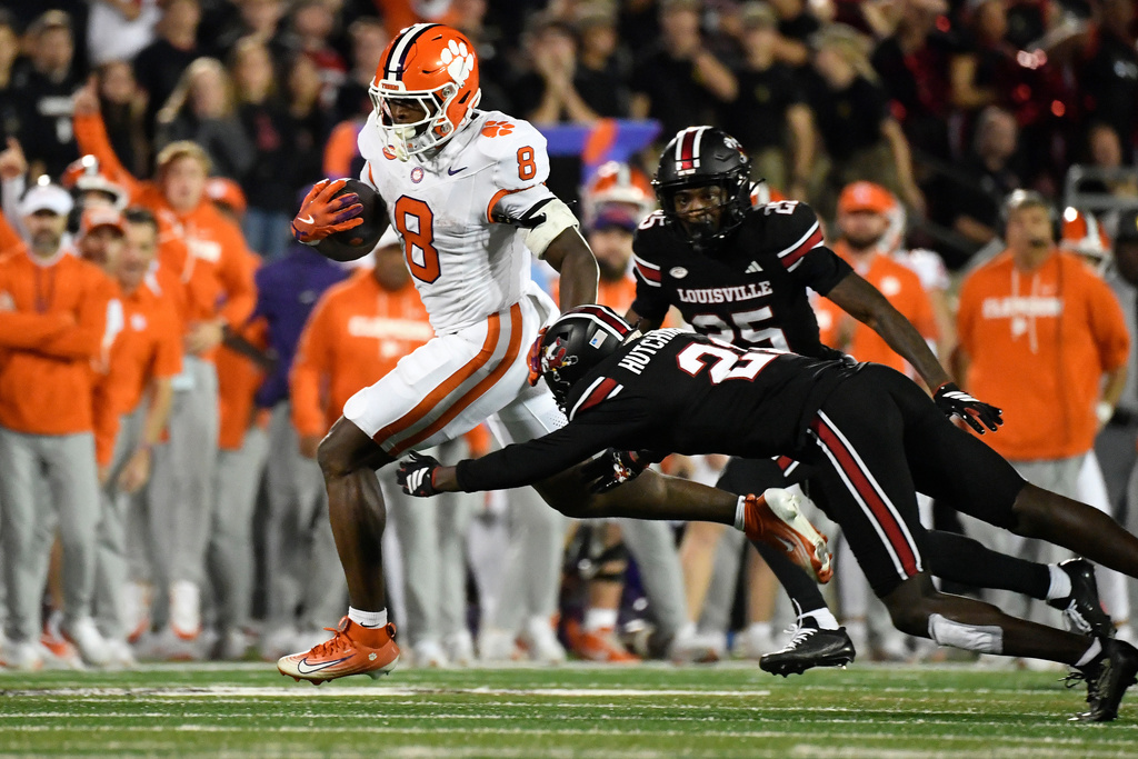 Clemson running back Adam Randall (8) attempts to avoid a diving tackle-attempt by Louisville defensive back D'Angelo Hutchinson, front right, during the second half of an NCAA college football game in Louisville, Ky., Friday, Nov. 14, 2025. (AP Photo/Timothy D. Easley)