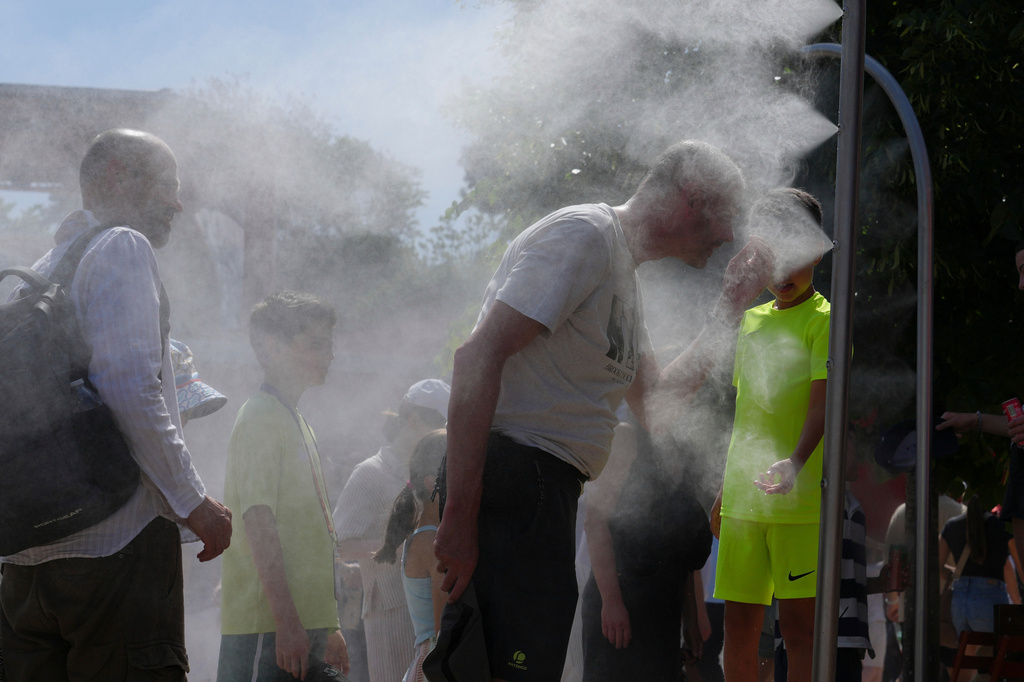 Visitors cool themselves with water from sprinklers during a hot day at the French Open tennis tournament in Paris, Monday, May 25, 2026. (AP Photo/Aurelien Morissard)
