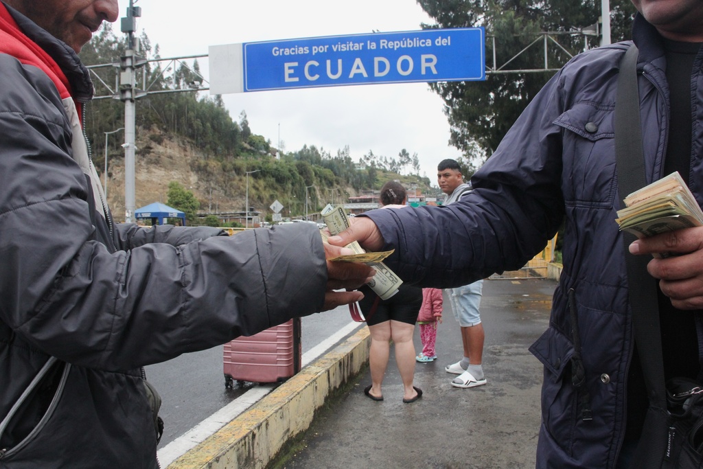 People exchange currencies at the Rumichaca international bridge between Colombia and Ecuador in Rumichaca, Colombia, Thursday, Jan. 22, 2026. (AP Photo/Leonardo Castro)