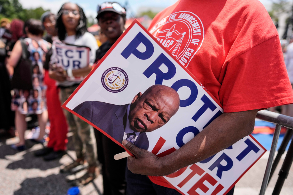A protestor holds a sign of the late Georgia Congressman John Lewis during a voting rally, Saturday, May 16, 2026, in Montgomery, Ala. (AP Photo/Mike Stewart)