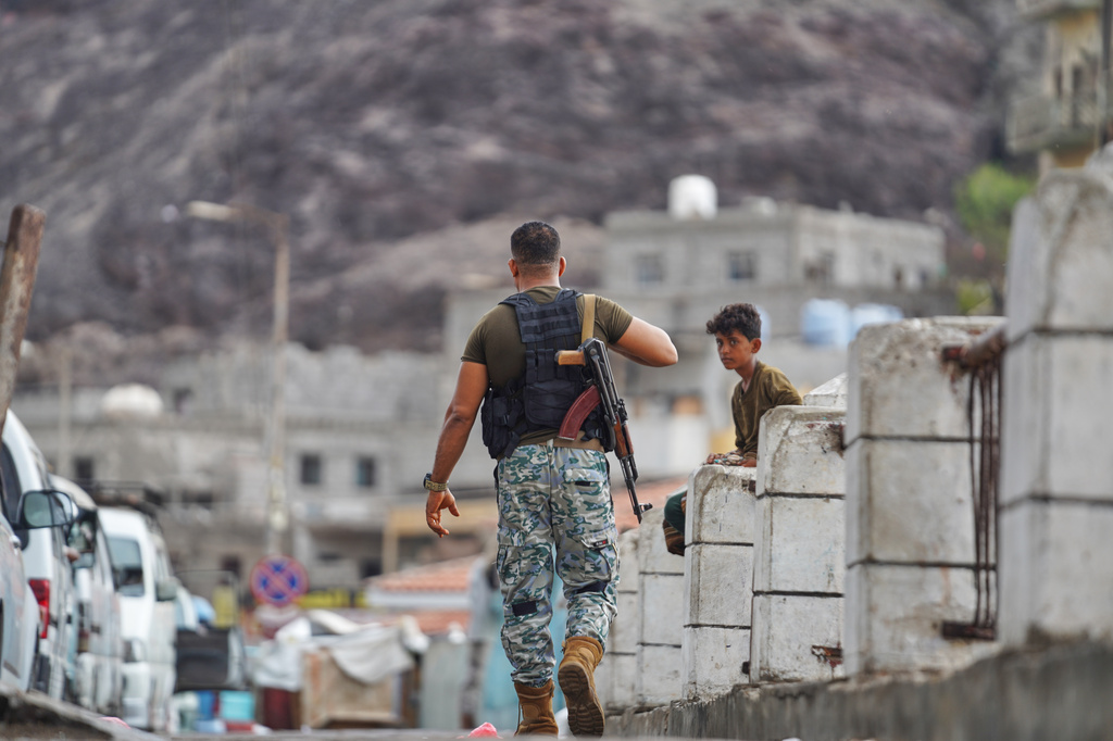 An armed man walks past a boy at the Sirah fish market in Aden, Yemen, Tuesday, Sept. 15, 2026. (AP Photo/Abdulnasser Alseddik)