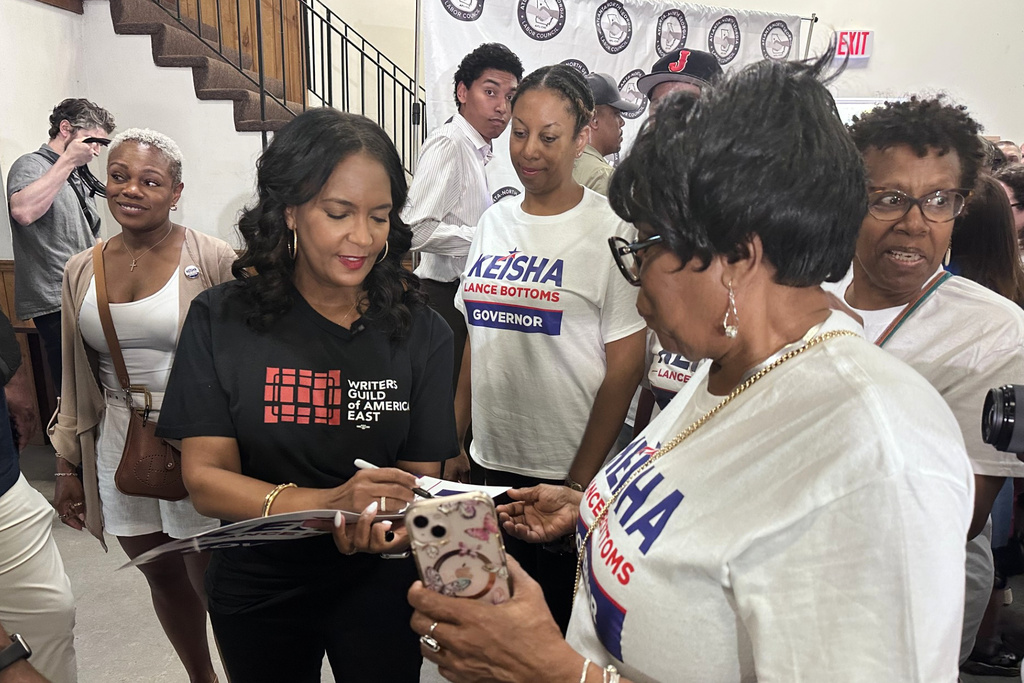 This photo taken with a smartphone shows Democratic gubernatorial candidate Keisha Lance Bottoms signing a campaign sign for a supporter during an Atlanta-North Georgia Labor Council (AFL-CIO) Labor Day lunch in Hapeville, Ga., Monday, Sept. 7, 2026. (AP Photo/Bill Barrow)